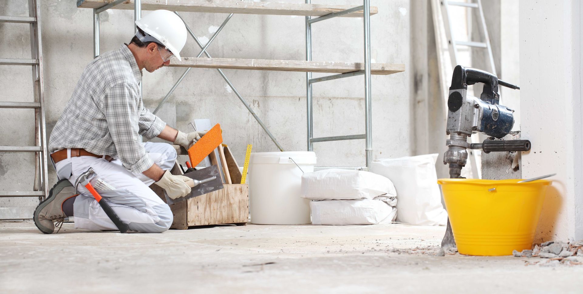 a construction worker is kneeling on the floor in a building under construction