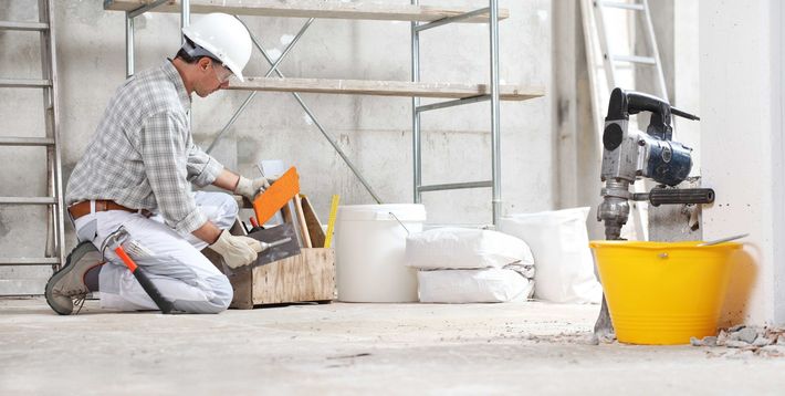a construction worker is kneeling on the floor in a building under construction