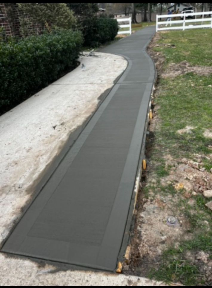 A concrete walkway with a white fence in the background