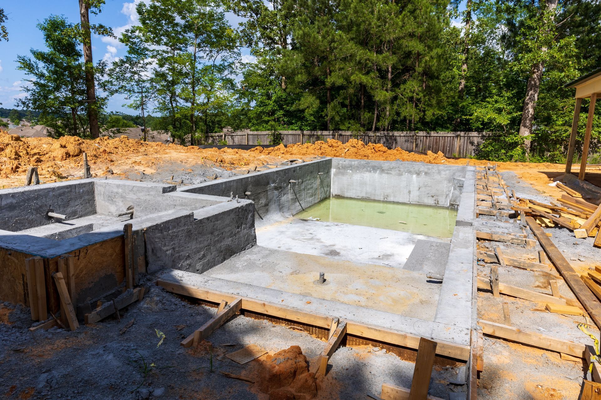 A swimming pool is being built in the backyard of a house.