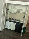 A small kitchen with white cabinets , a black dishwasher , and a sink.