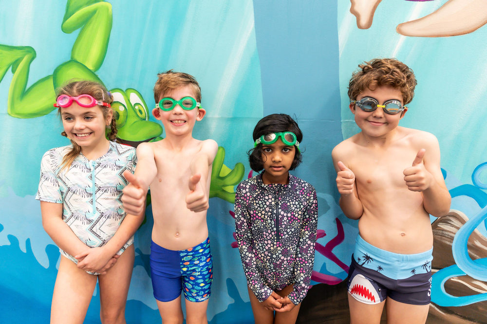Four kids at Col Jones Swim Tempe smiling and enjoying the swimming program.