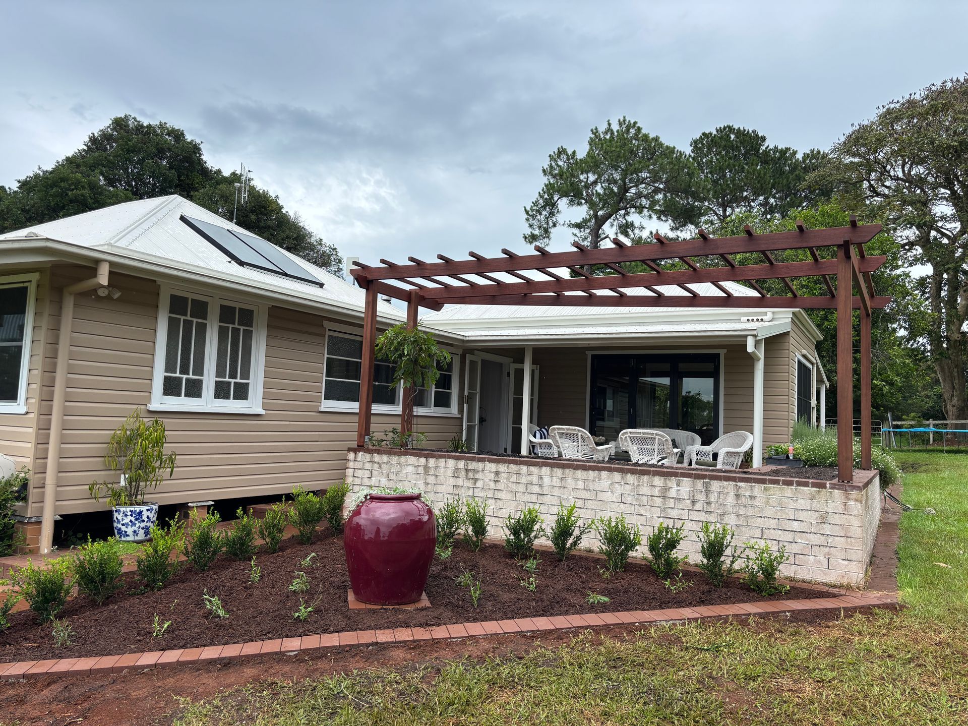 A Brick house has a garden by entrance with a large pot — Tim Williams Landscapes in Wollongbar, NSW