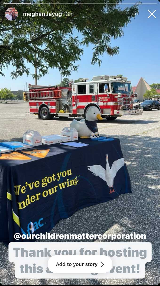 Table with "Our Children Matter Corporation" logo and a fire truck in a parking lot.