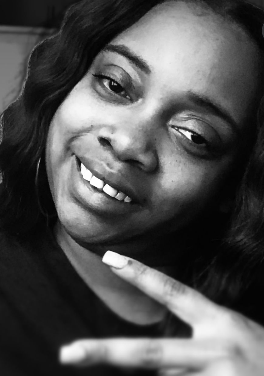 Woman smiling, making peace sign with hand, in black and white.