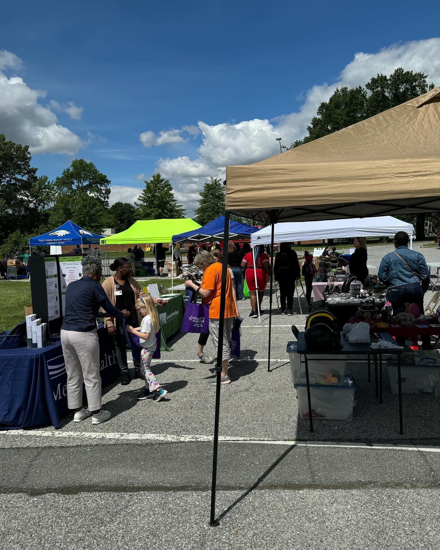 Outdoor fair with booths and people under tents on a sunny day.