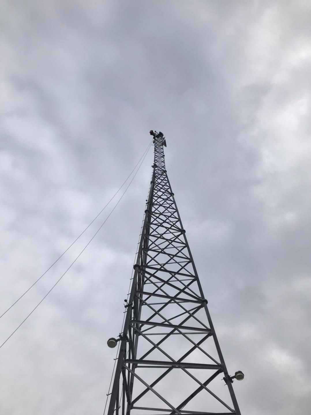 A tall metal communications tower against a cloudy sky.