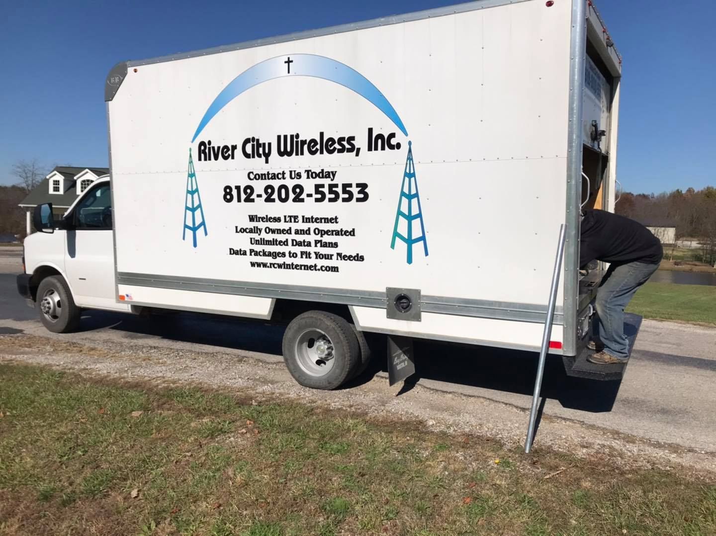 White River City Wireless truck with person loading at the back, blue logo, parked on a gravel area.