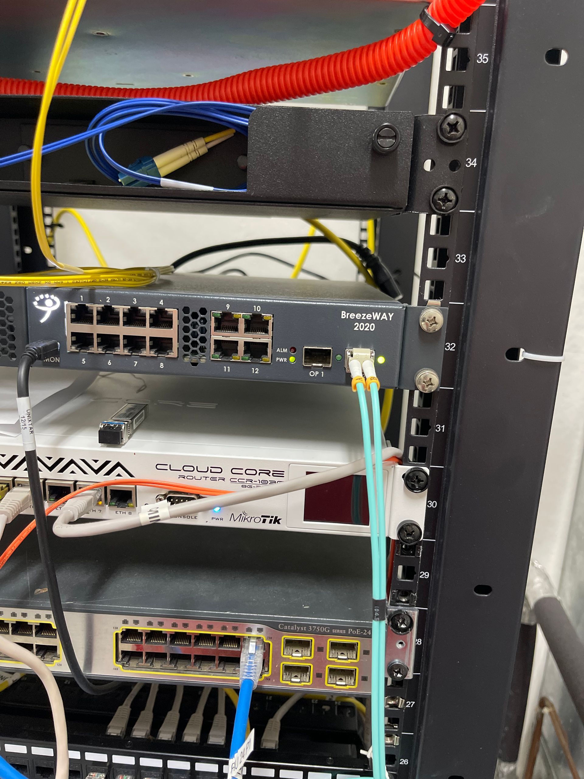 Network equipment rack with switches, cables, and fiber optic connections.