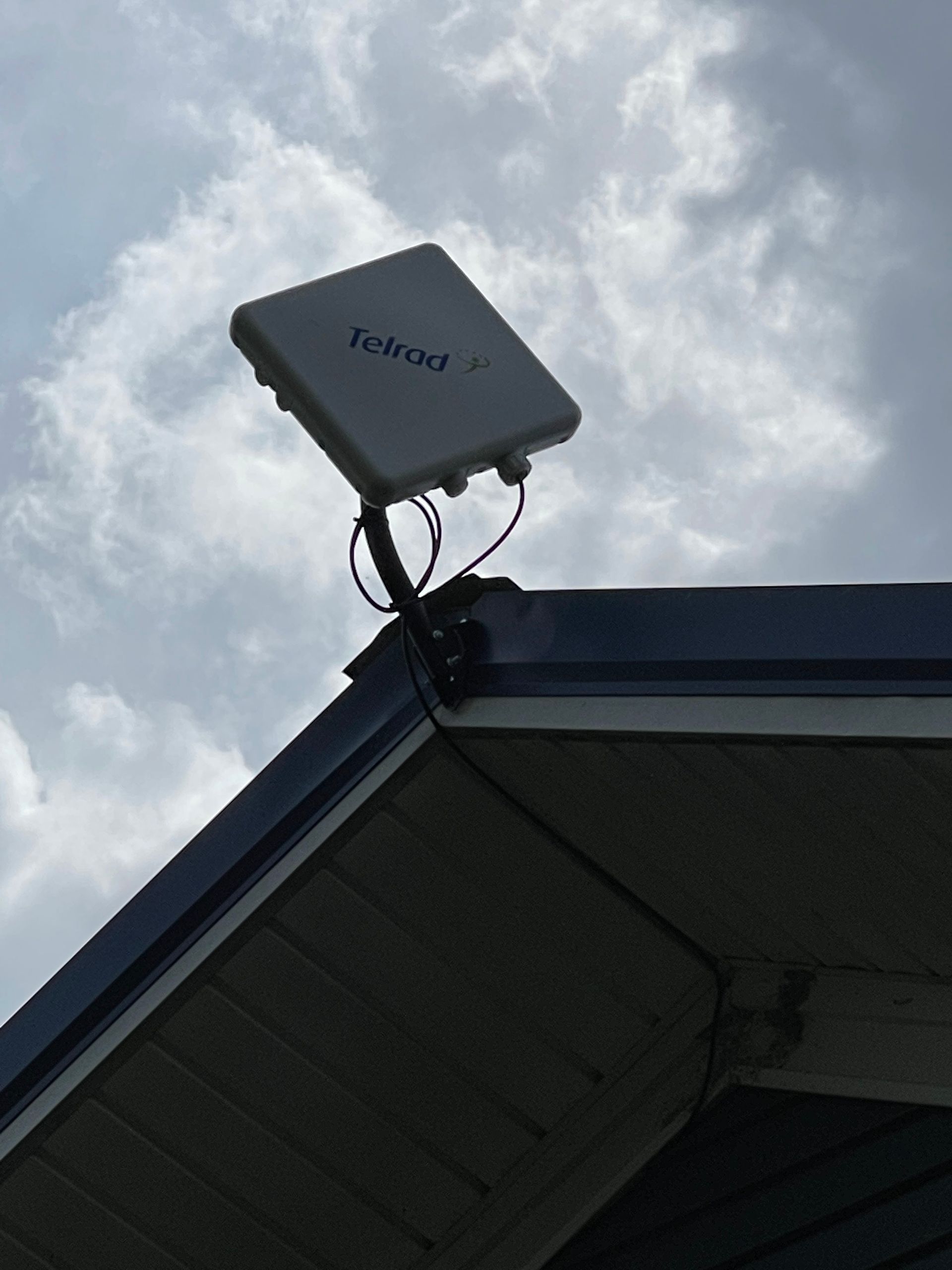 White antenna on a roof against a cloudy sky.
