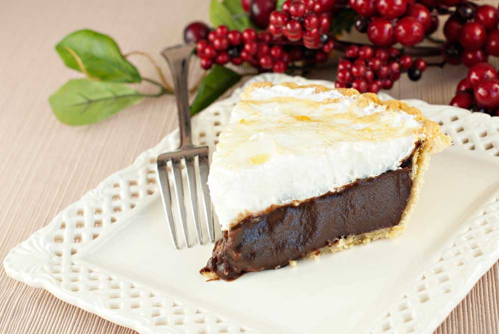 A piece of homemade chocolate meringue pie on a plate with a fork