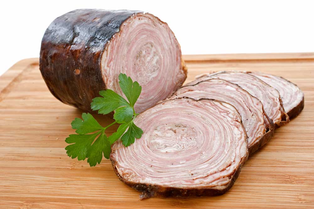 Andouille de Guemene, french sausage on a cutting board with parsley