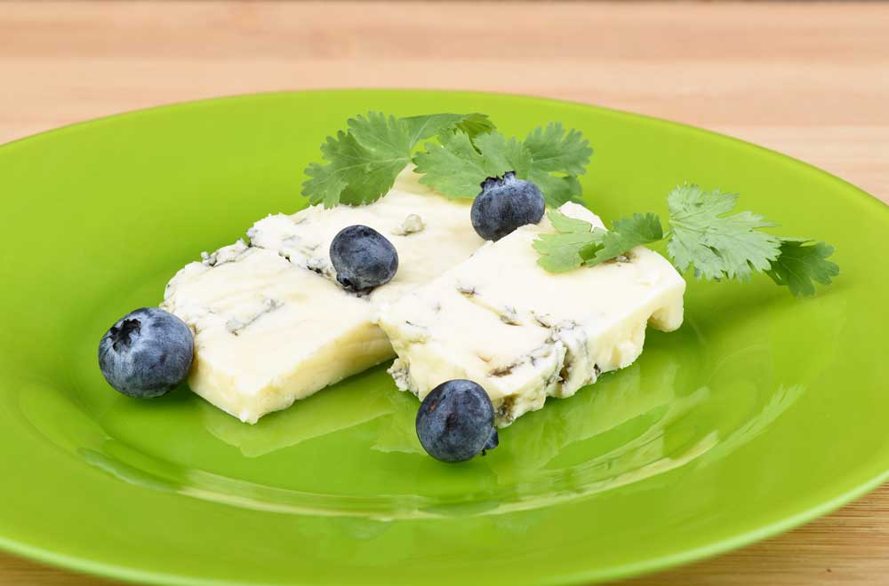 Blueberries and cilantro leaves on slices of delicious blueberry stilton