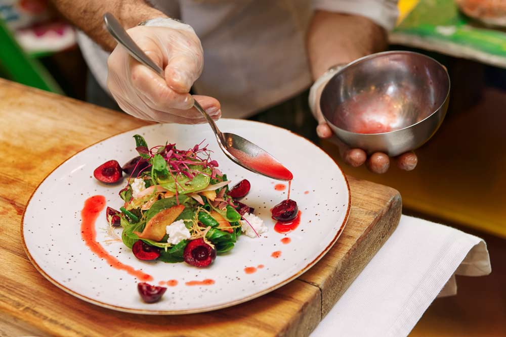 Chef is adding sauce to vegetable appetizer