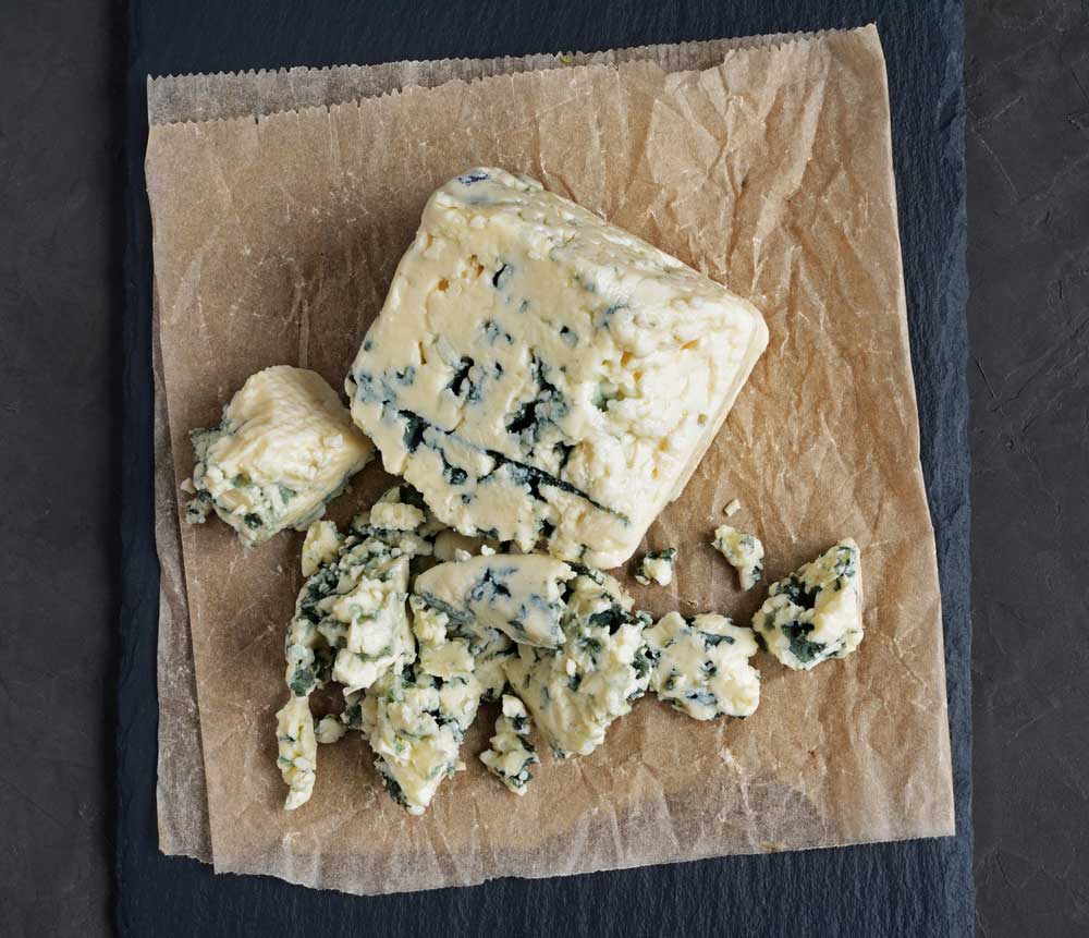 A piece of blue cheese is sitting on a piece of brown paper.