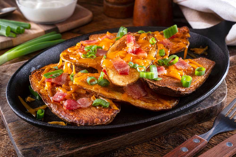 Delicious homemade potato skins with melted cheese, bacon, green onions and sour cream