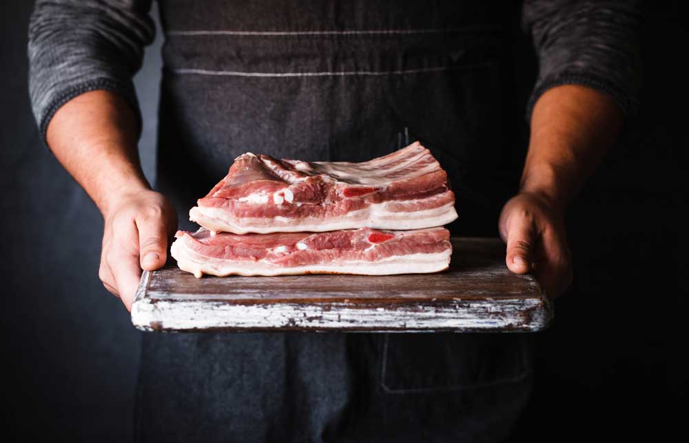 Farm fresh Pork Belly butcher person curring bacon porchetta