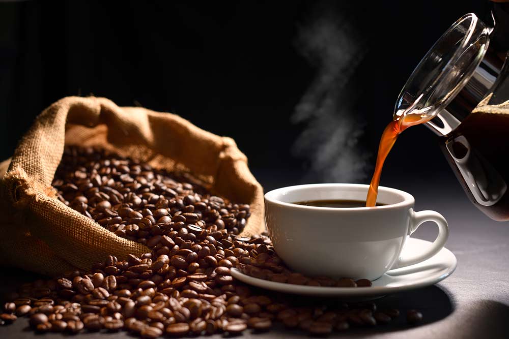 Pouring coffee with smoke on a cup and coffee beans