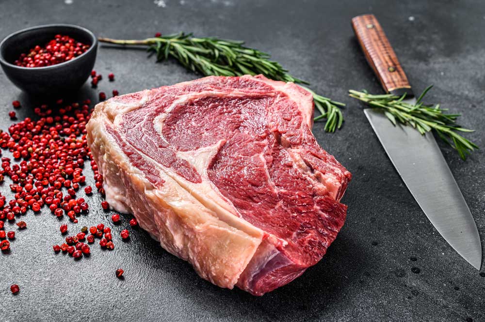 Raw cowboy steak or ribeye on the bone with herbs