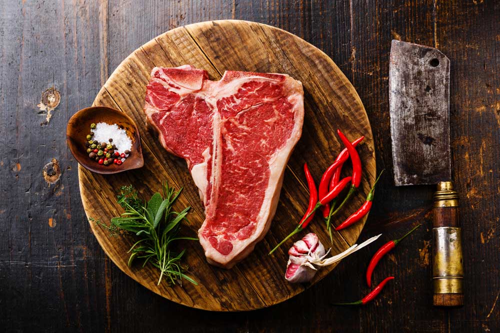 Raw meat T-bone steak, seasoning and cleaver