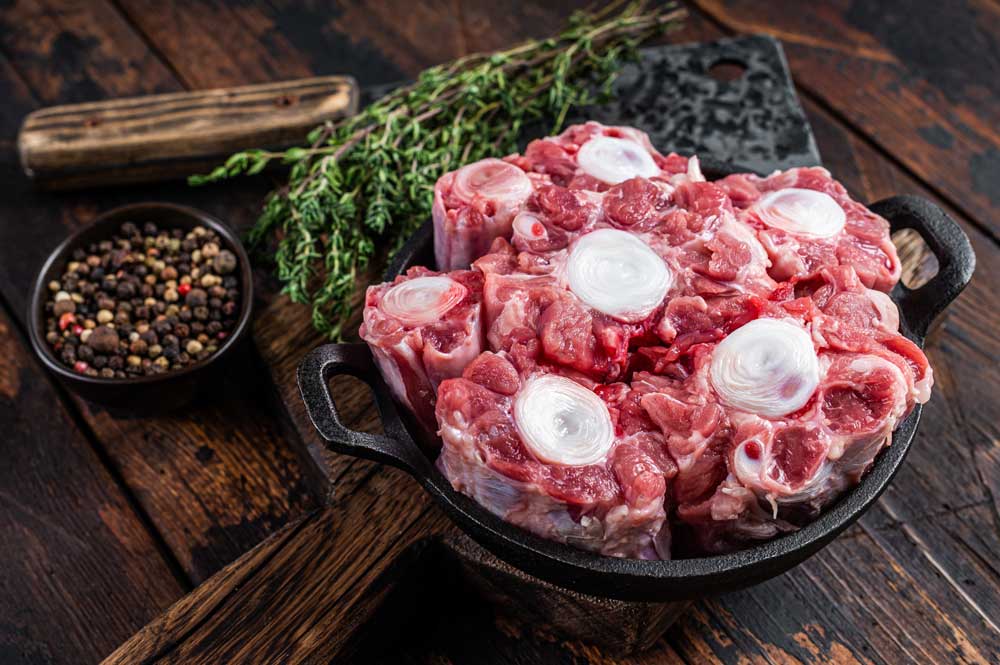 Raw veal beef Oxtail Meat on butcher wooden board with cleaver