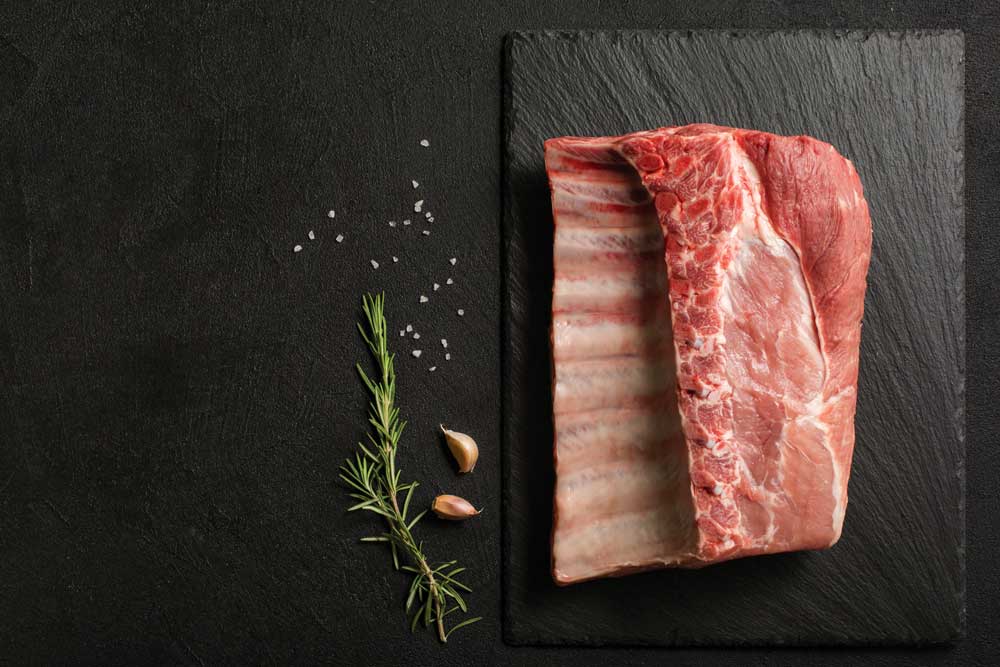 Uncooked Pork Ribs on a stone kitchen cutting board