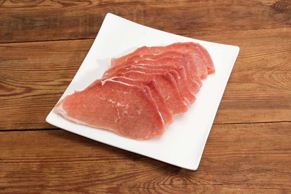 Uncooked defrosted pork slices on the square dish