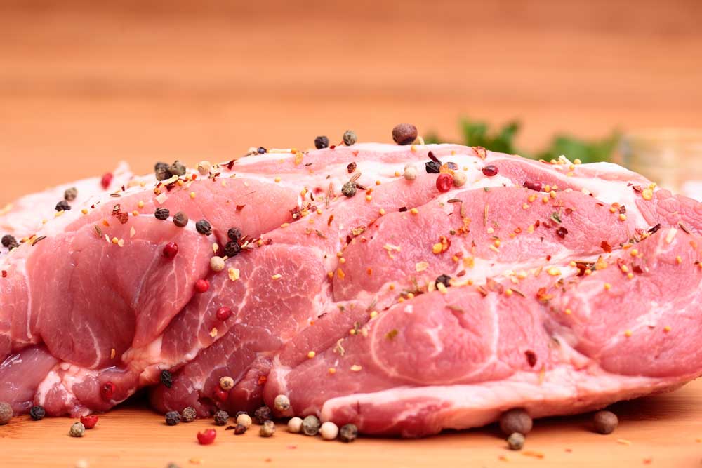 fresh raw pork chop with tomatoes, greens, spices and garnet