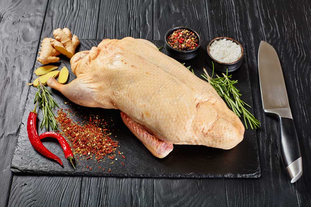 Top of view rustic wooden cutting board on dark background with duck thigh