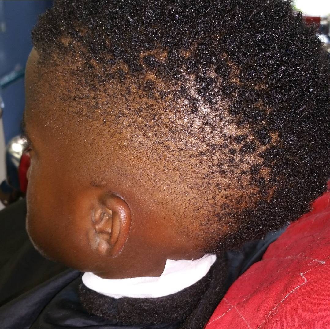 A young boy is getting his hair cut by a barber