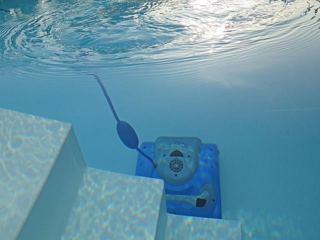 Underwater view of a blue pool cleaner attached to steps in a pool.