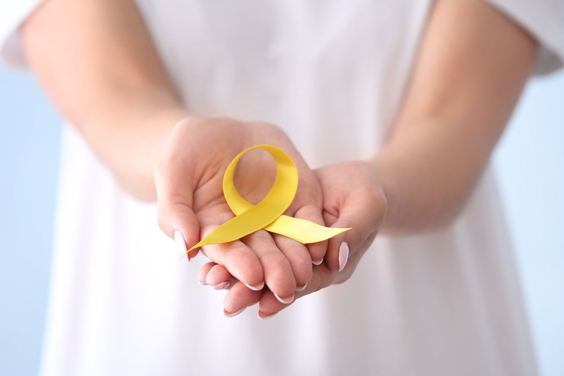 Mãos segurando fita amarela como símbolo de conscientização sobre Endometriose Intestinal