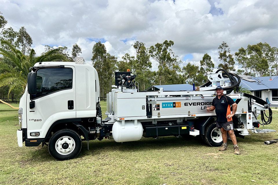 A man is standing next to a white truck in a field.