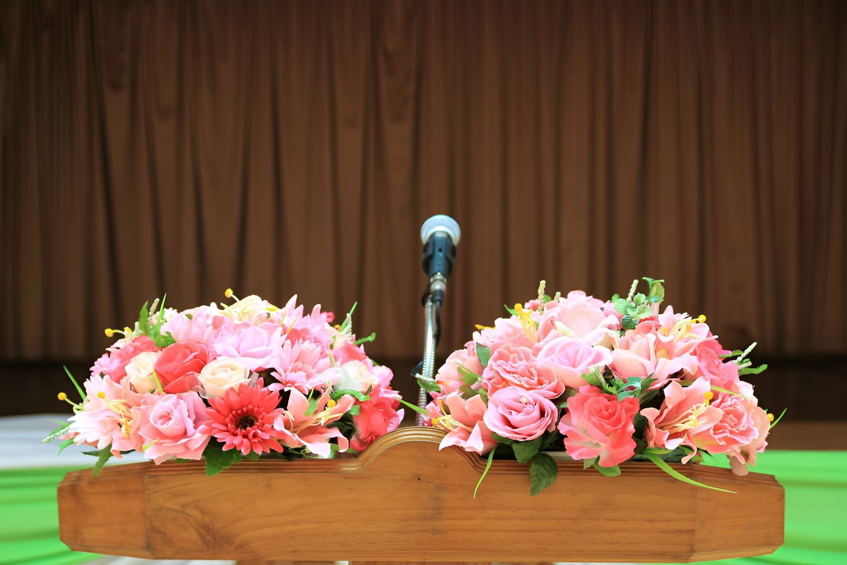 A Podium With Flowers and a Microphone on It — Mid Coast Funeral and Cremation Service In Port Macquarie, NSW