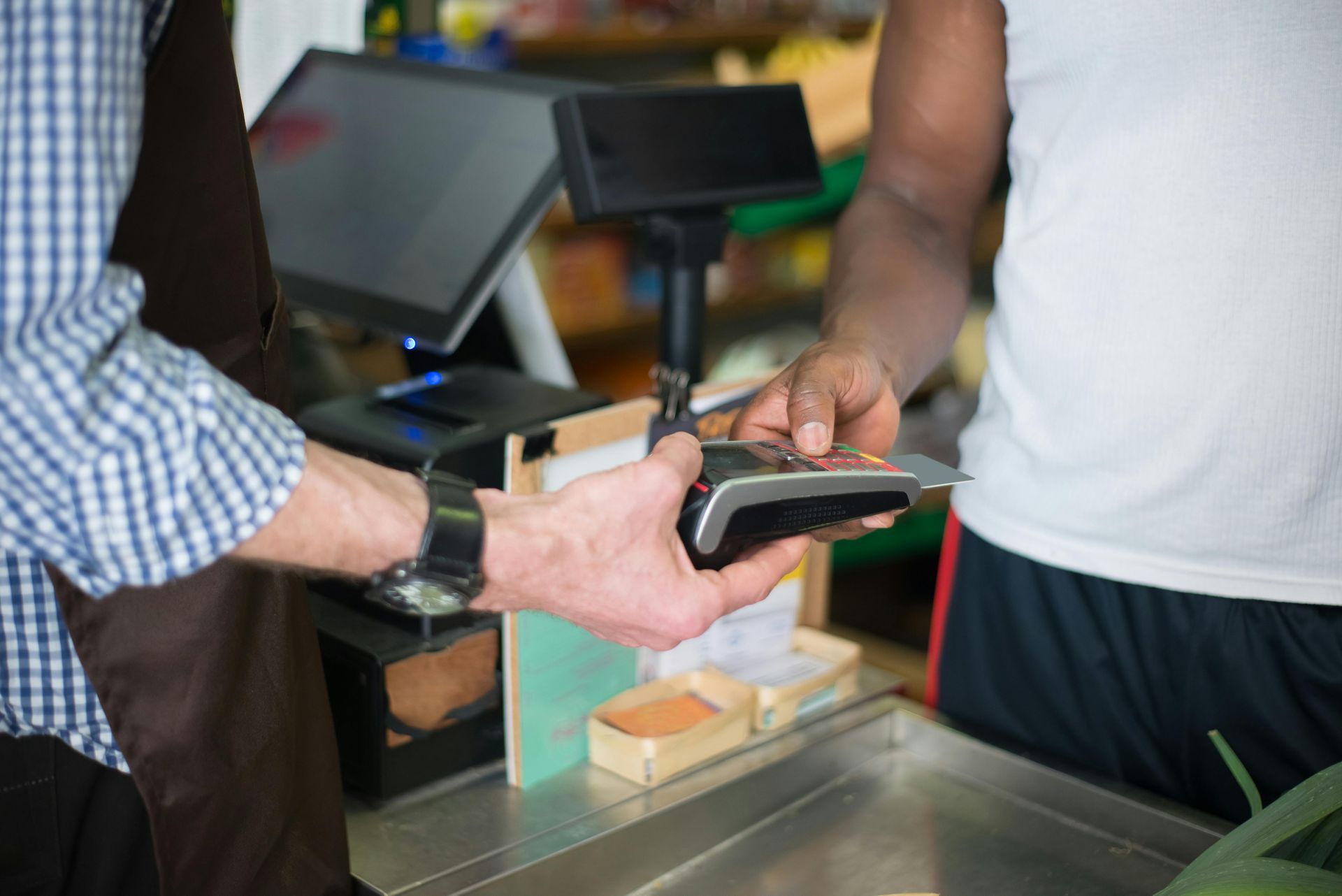 A customer using a credit card at a checkout counter in a grocery store.