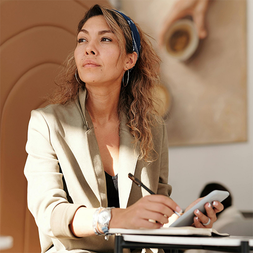 Woman with long brown hair and a blazer looking into the distance