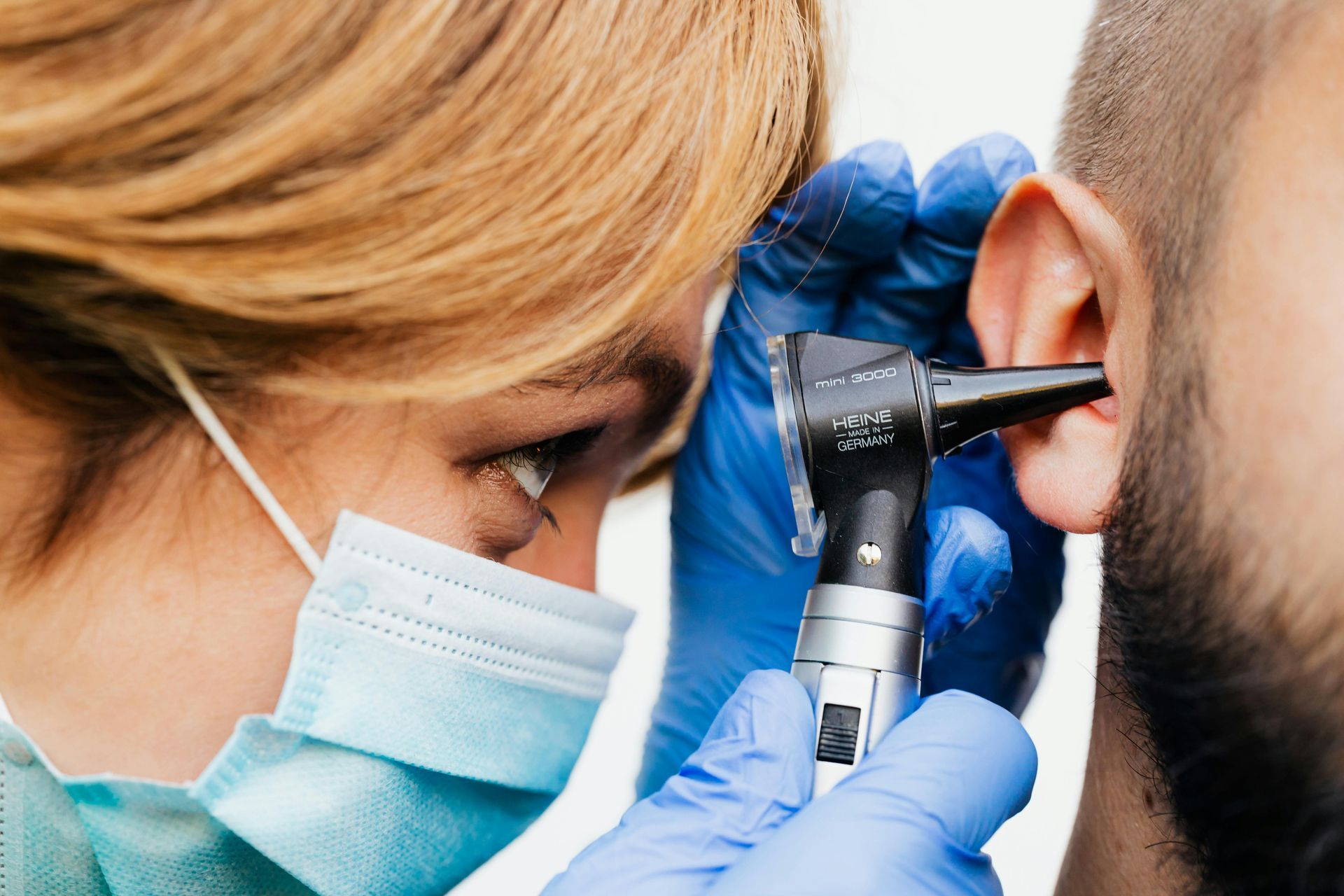 A hearing specialist examining a patient's ear with an otoscope