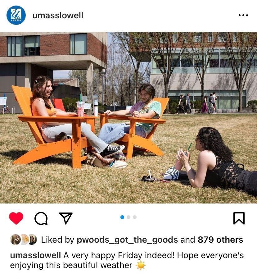 Three students relaxing on a sunny day at UMass Lowell. Two sit in orange chairs, one reclines on the grass.
