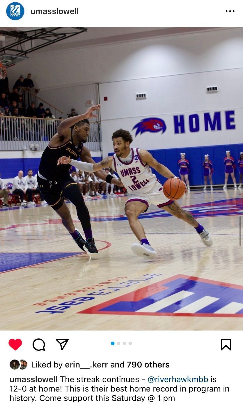 Basketball players on court; one dribbles while defended. 
