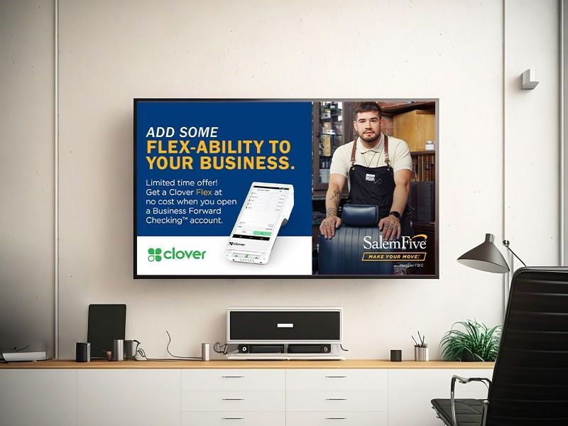 A TV displays a Clover ad. Man in apron stands near barrels. Ad reads: Add flex-ability to your business.