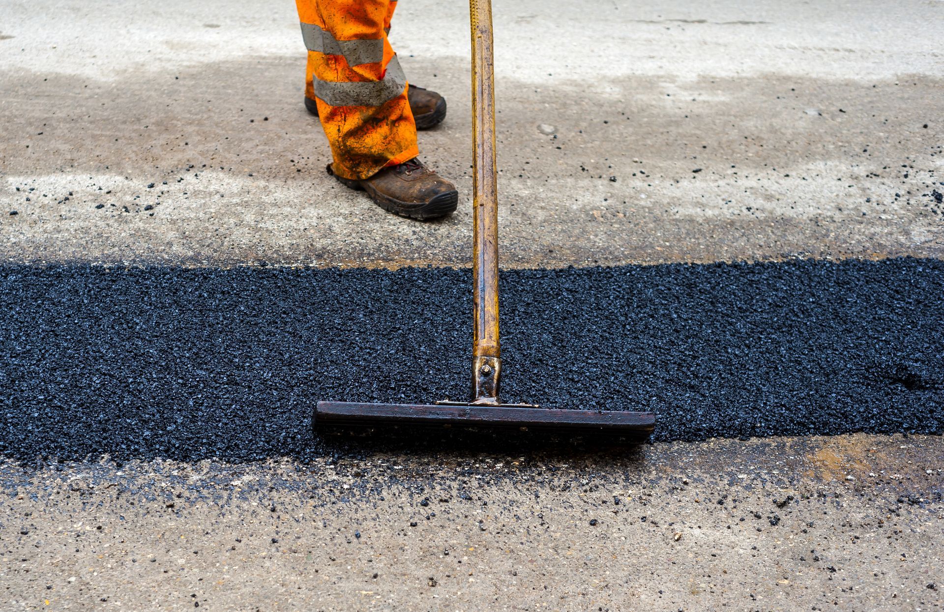 A man is sweeping the asphalt with a broom.