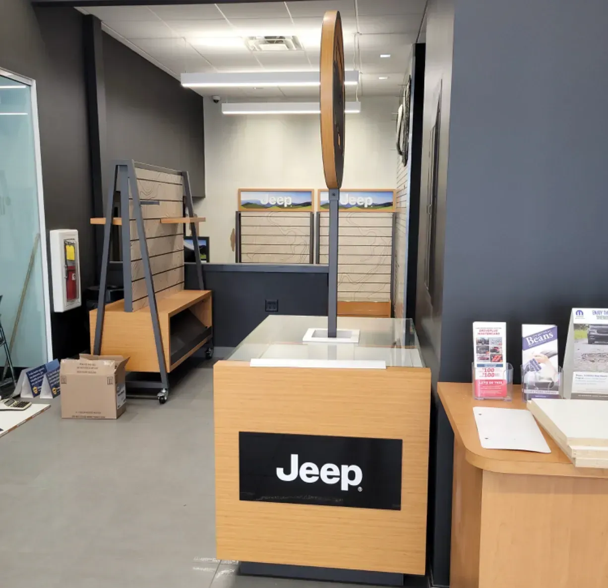 Jeep showroom display with wooden pedestal and large vertical sign in a showroom interior