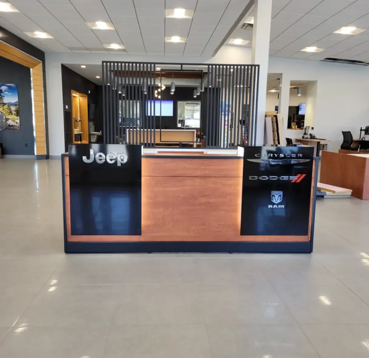 Jeep dealership reception desk with wood front, black panels, and showroom seating in the background
