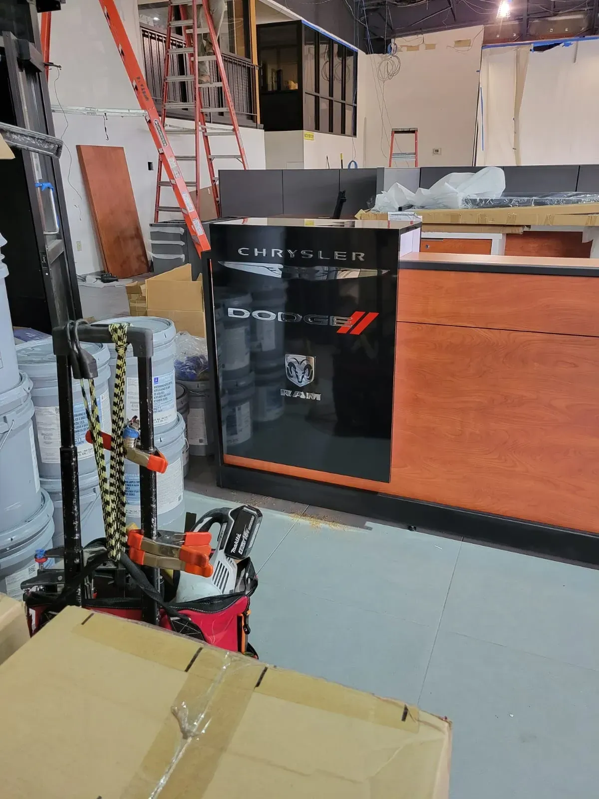 Construction site interior with ladders, tools, wood panels, and a black sign in the foreground