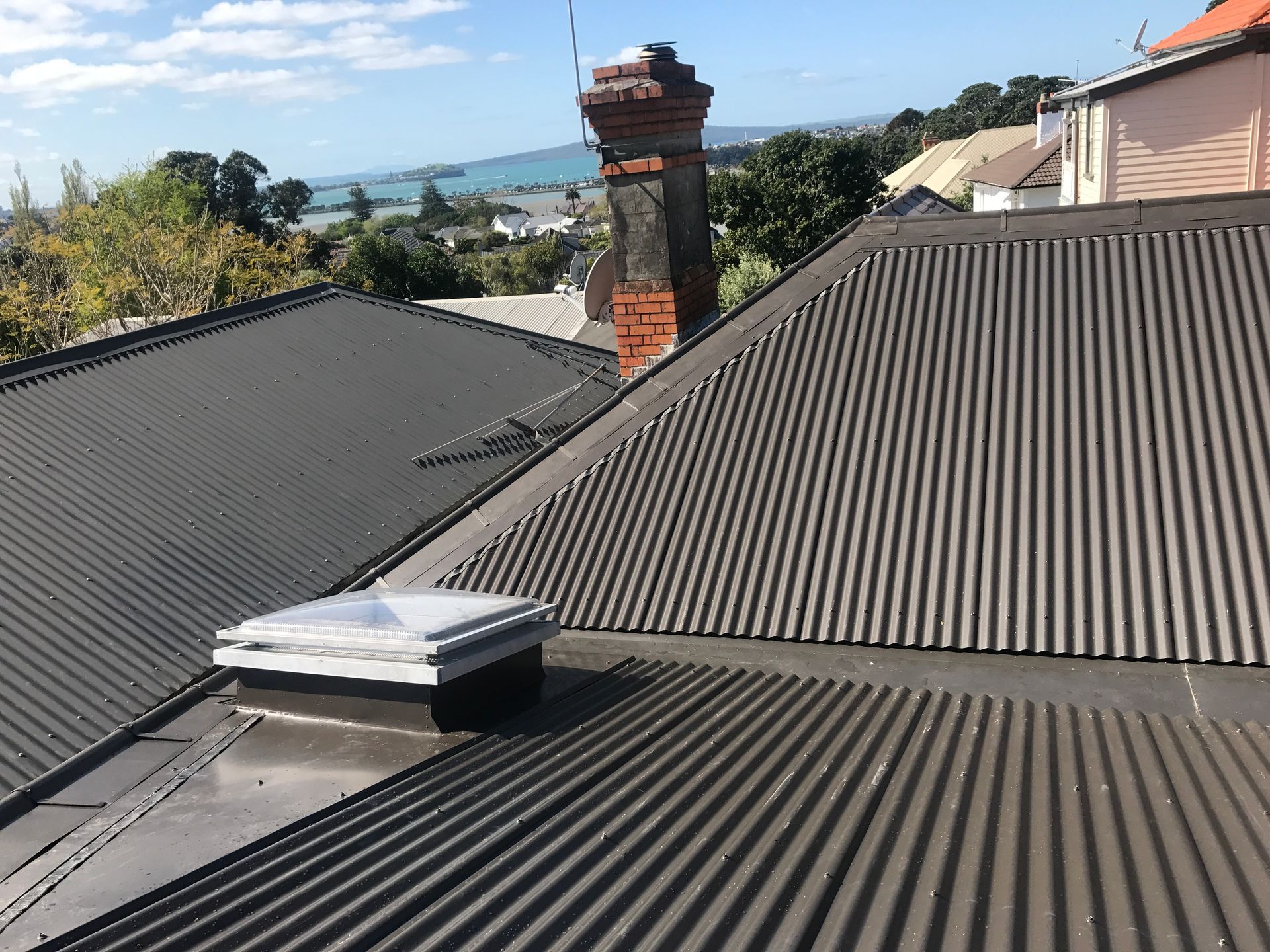 Black gutter on a house with a gray shingle roof and tan siding.