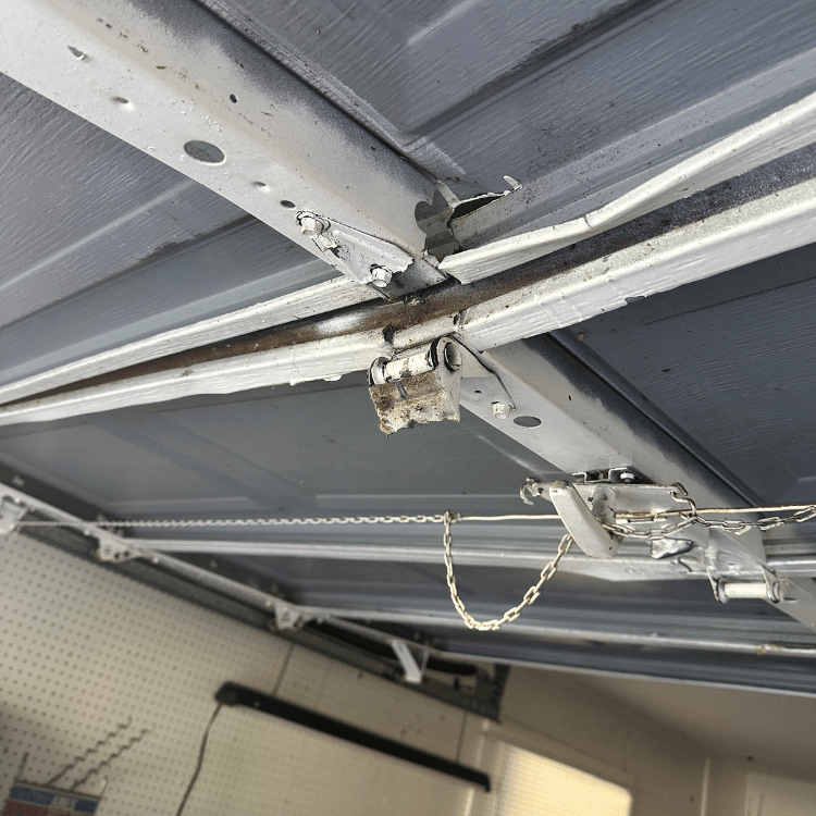 A close-up view of the interior mechanism and hinge of an overhead garage door, showing metallic hardware and parts.