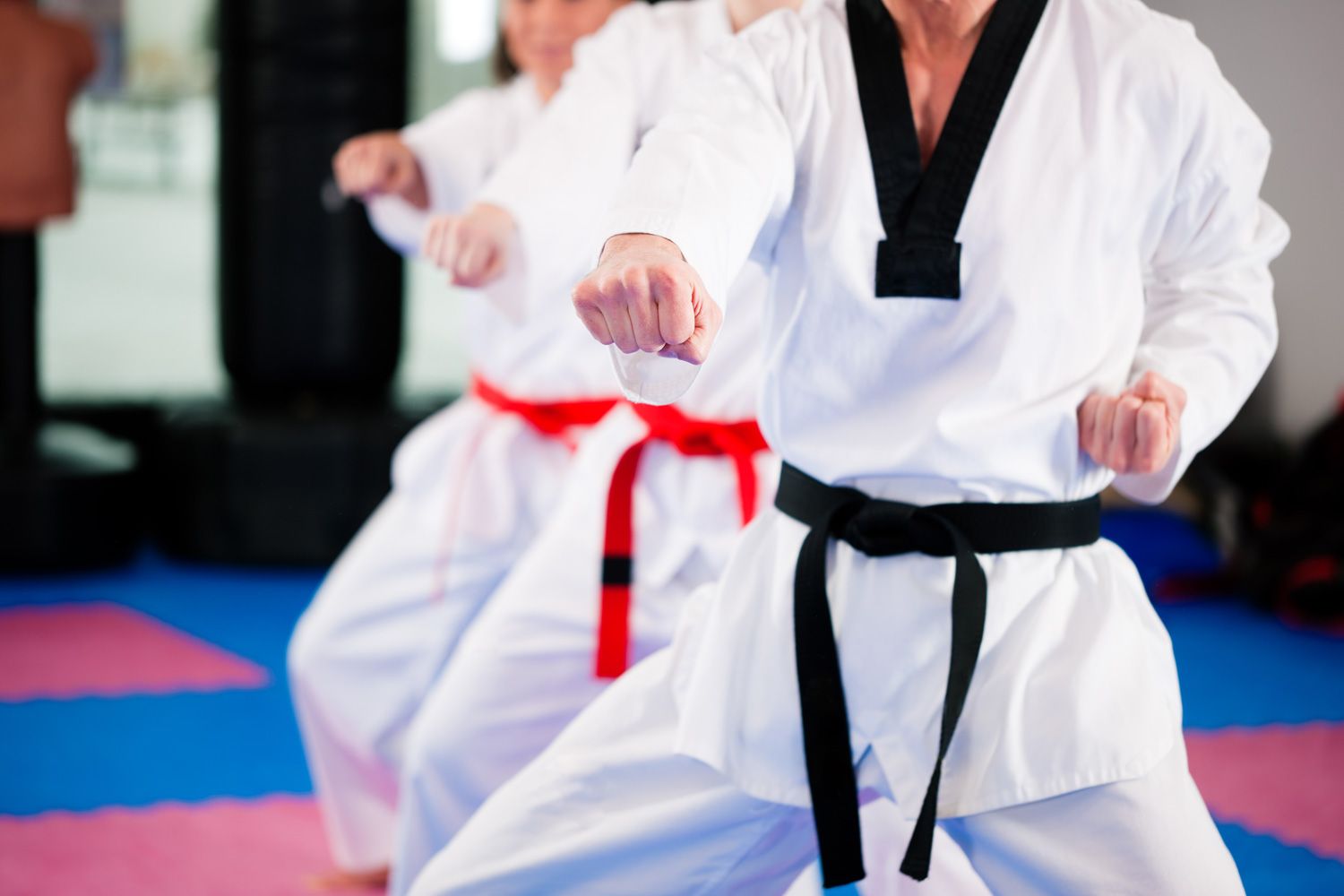 People in a gym in martial arts training, the trainer has a black belt