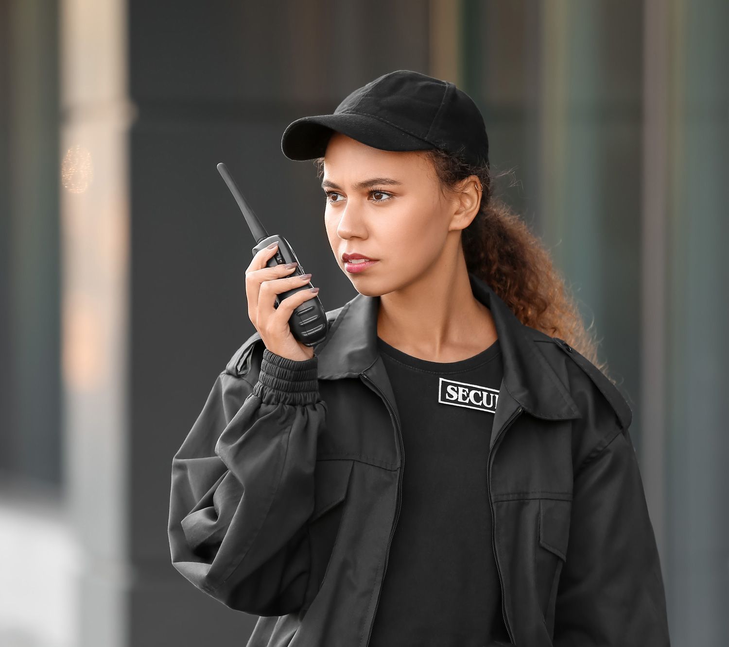female security guard with radio transmitter near building outdoors