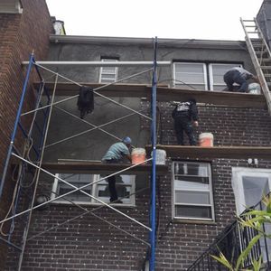 A group of men are working on a brick building with scaffolding.