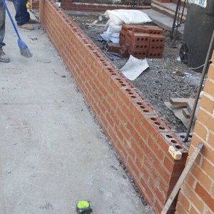 A man is standing next to a brick wall.